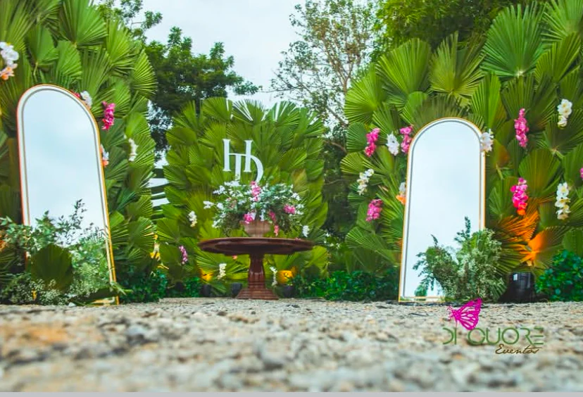 Cenário de casamento ao ar livre com espelhos dourados e parede verde